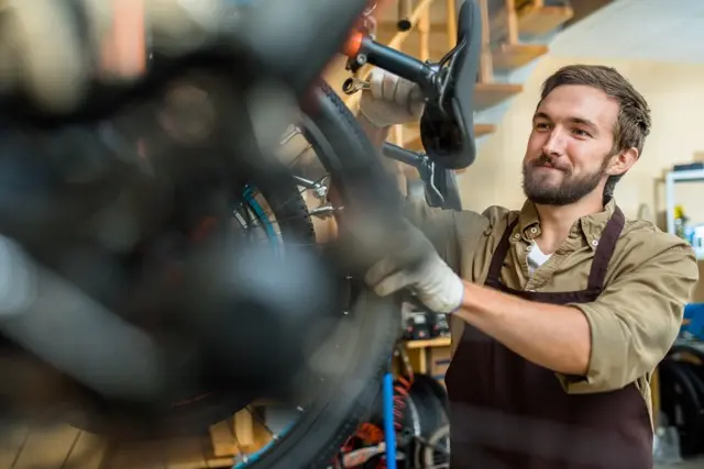 Fietsenmaker stelt versnellingen af met een sleutel aan een fietswiel